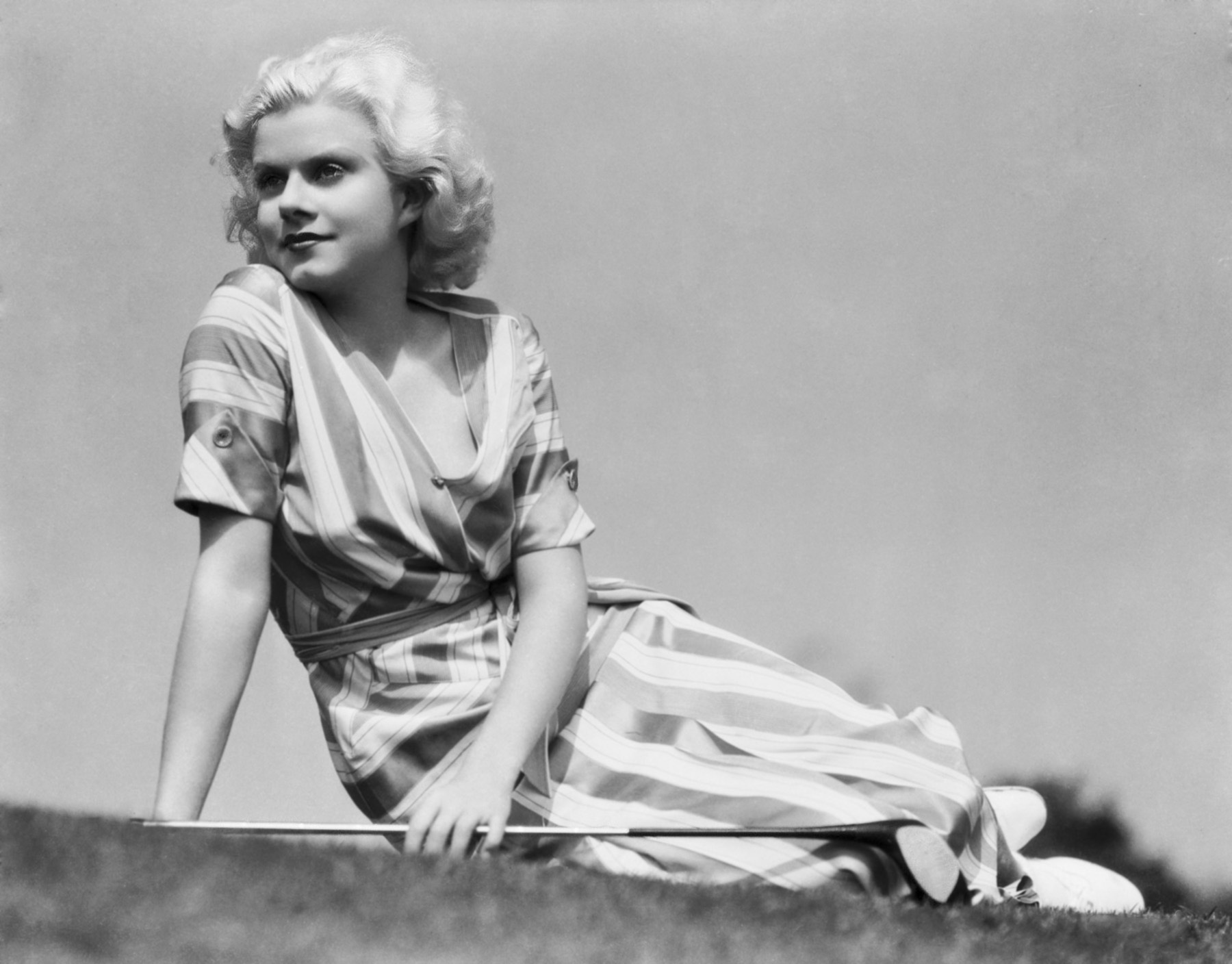 1932: Actress Jean Harlow (1911 - 1937) takes a breather between greens on the golf course dressed in a striped summer dress. (Photo by Clarence Sinclair Bull)